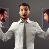 Mężczyzna z przerażoną miną trzyma po bokach zdjęcia swojej głowy, ukazujące gniew. Symbolizuje to walkę z najcięższymi chorobami psychicznymi.