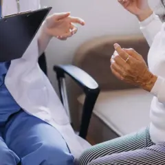 Lekarz w białym fartuchu rozmawia z pacjentką, notując coś na kartce. Czy do psychiatry potrzebne jest skierowanie?