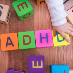 Dziecko układa klocki z literami ADHD. To pokazuje, że spektrum co to jest, może być złożone.