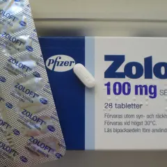 Opakowanie i blister leku Zoloft 100 mg z sertraliną, obok pojedyncza tabletka.