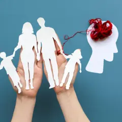 Rodzina z papieru połączona czerwoną nitką z głową, sugerując, czy choroby psychiczne są dziedziczne.