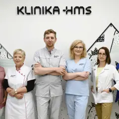 Zespół medyczny w uniformach stoi przed napisem "KLINIKA HMS".