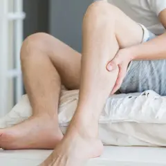 Mężczyzna trzyma się za łydkę, odczuwając ból. Może to być jeden z objawów miażdżycy, który wpływa także na psychikę.