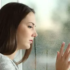 Smutna dziewczyna z dłonią na zaparowanym oknie, czuje się inaczej, chandra.