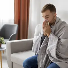 Mężczyzna owinięty kocem, z chusteczką przy nosie, może sugerować objawy choroby, ale czasem to tylko pozory, jak w przypadku zespołu Munchausena.