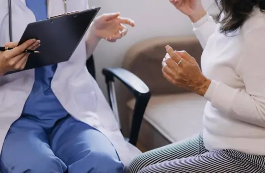Lekarz w białym fartuchu rozmawia z pacjentką, notując coś na kartce. Czy do psychiatry potrzebne jest skierowanie?
