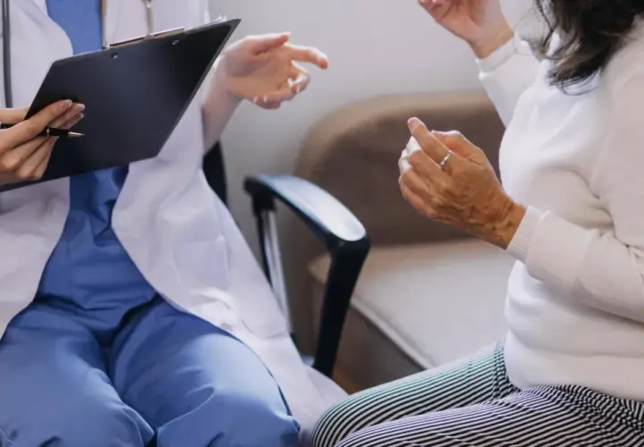 Lekarz w białym fartuchu rozmawia z pacjentką, notując coś na kartce. Czy do psychiatry potrzebne jest skierowanie?