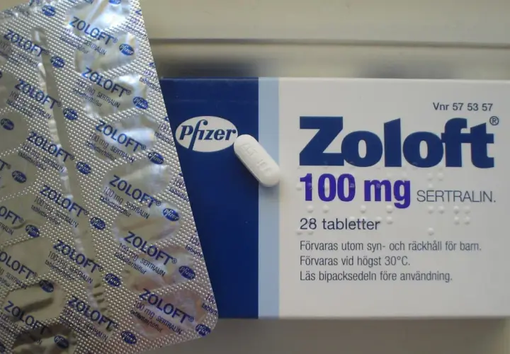 Opakowanie i blister leku Zoloft 100 mg z sertraliną, obok pojedyncza tabletka.