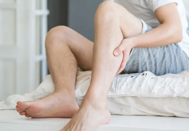 Mężczyzna trzyma się za łydkę, odczuwając ból. Może to być jeden z objawów miażdżycy, który wpływa także na psychikę.