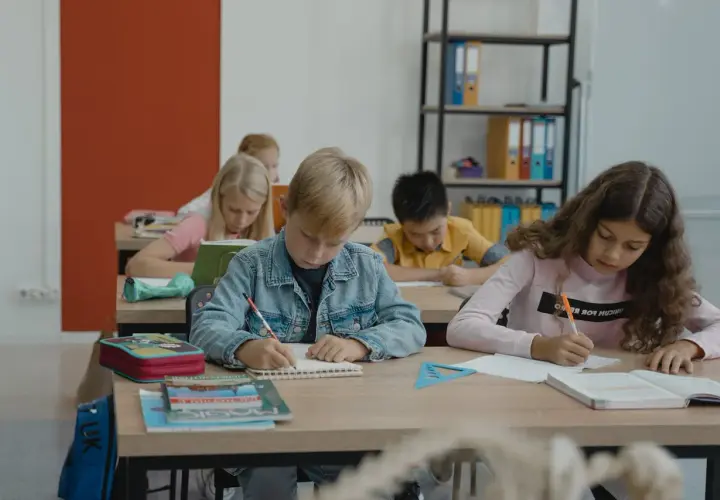 Dzieci piszą w zeszytach, ale jedno z nich, z fobią szkolną, czuje się zagubione.