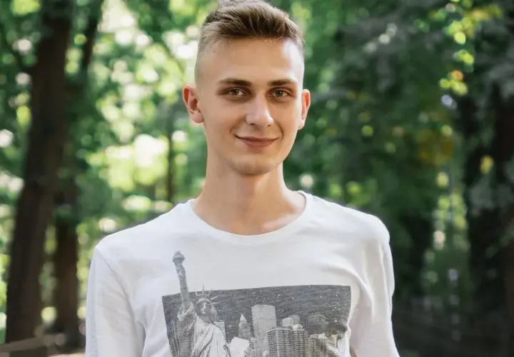 Uśmiechnięty nastolatek w białej koszulce z grafiką Nowego Jorku. Może to być przykład, jak zespół Aspergera objawy u nastolatków mogą być subtelne.