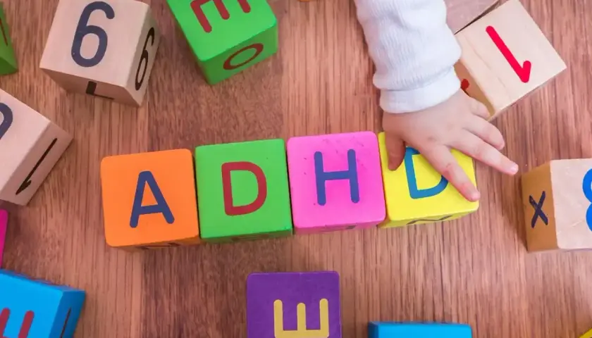 Dziecko układa klocki z literami ADHD. To pokazuje, że spektrum co to jest, może być złożone.