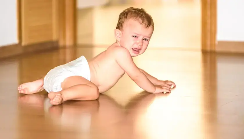 Płaczący niemowlak w pieluszce na podłodze. Czy to pierwsze oznaki adhd u niemowlaka, czy po prostu zły humor?