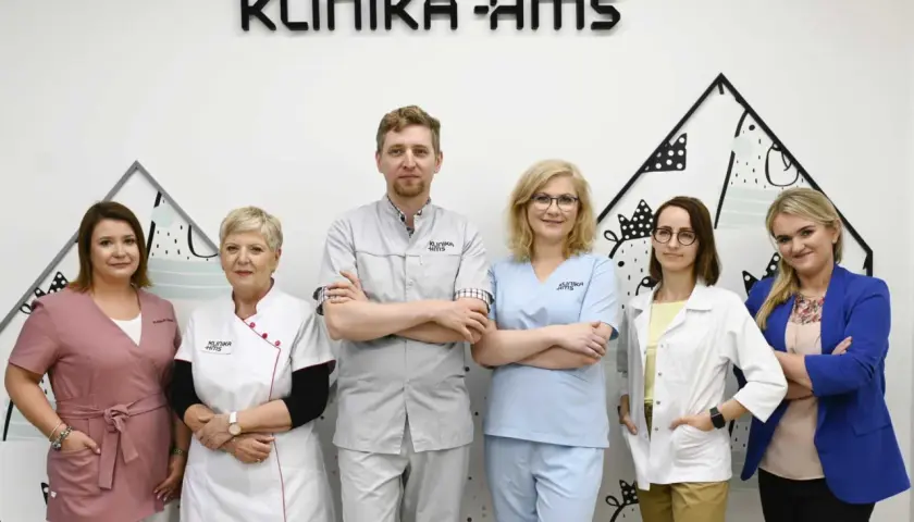 Zespół medyczny w uniformach stoi przed napisem "KLINIKA HMS".