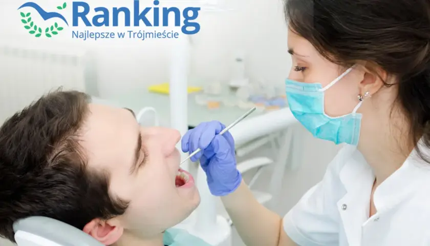 Dentystka w masce bada zęby pacjenta stomatologicznym narzędziem.