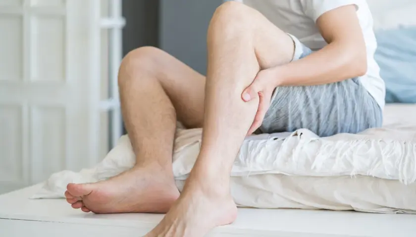 Mężczyzna trzyma się za łydkę, odczuwając ból. Może to być jeden z objawów miażdżycy, który wpływa także na psychikę.
