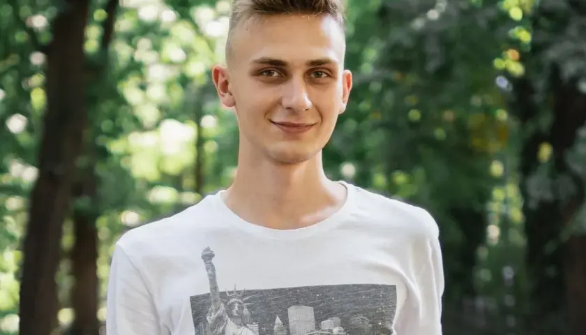 Uśmiechnięty nastolatek w białej koszulce z grafiką Nowego Jorku. Może to być przykład, jak zespół Aspergera objawy u nastolatków mogą być subtelne.