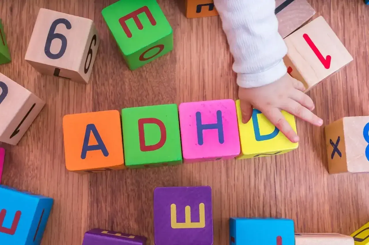 Dziecko układa klocki z literami ADHD. To pokazuje, że spektrum co to jest, może być złożone.