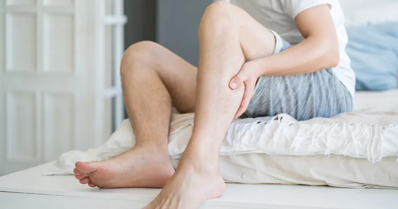 Mężczyzna trzyma się za łydkę, odczuwając ból. Może to być jeden z objawów miażdżycy, który wpływa także na psychikę.