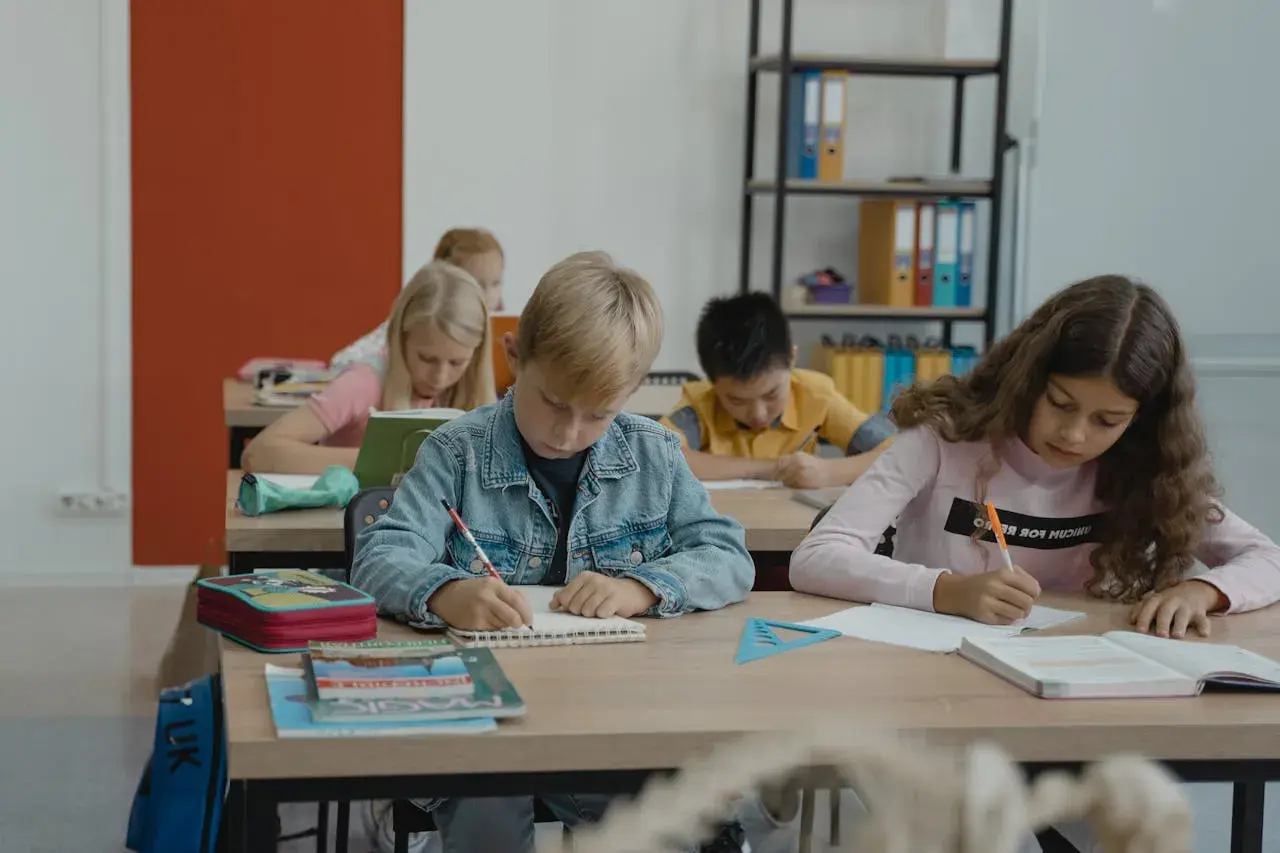 Dzieci piszą w zeszytach, ale jedno z nich, z fobią szkolną, czuje się zagubione.