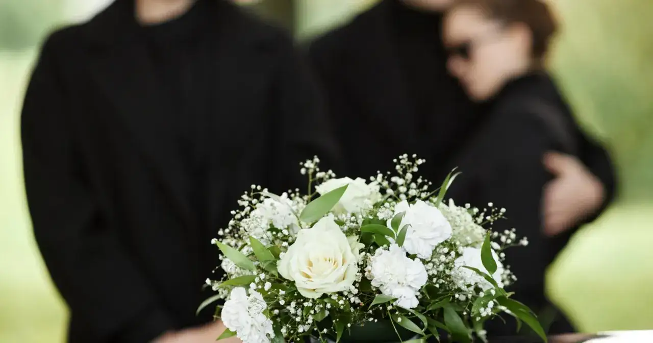 Pogrzeb. W smutku i żałobie, z bukietem białych róż, czuć syndrom wdowy.