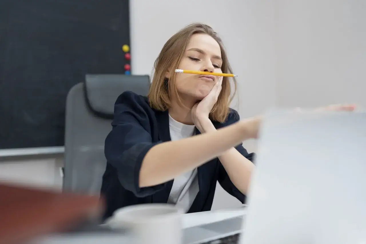 Kobieta z ołówkiem w ustach, zamyślona, może to być jeden z objawów ADHD u kobiet.